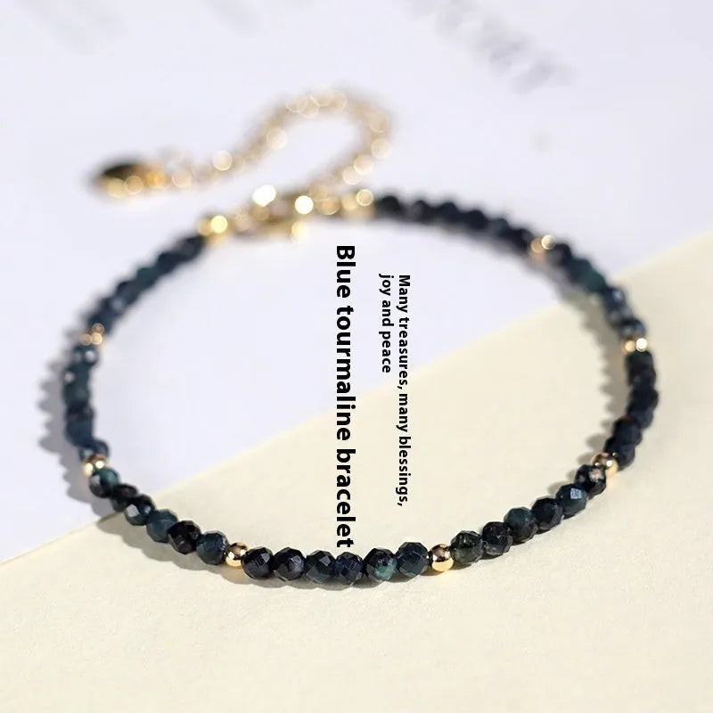 Close-up of a blue tourmaline beaded bracelet with 3mm stones and spacer beads on a wrist.