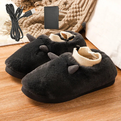 USB-powered electric slippers in black with a connected USB cable, showing soft velvet upper and plastic sole.