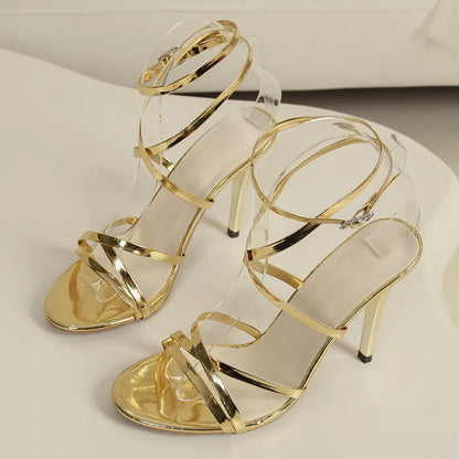 Gold women's stiletto sandals with buckle fastening on ankle cross-straps and pointed toe.
