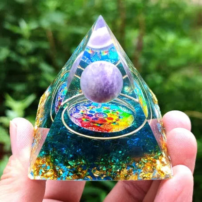A small 6cm clear epoxy resin pyramid ornament containing pieces of natural crystal gravel on a flat surface.