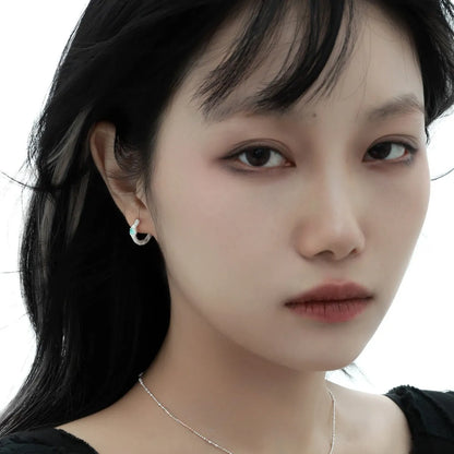 A pair of geometric round ear clips made from 925 silver with a burnt silver electroplated finish.