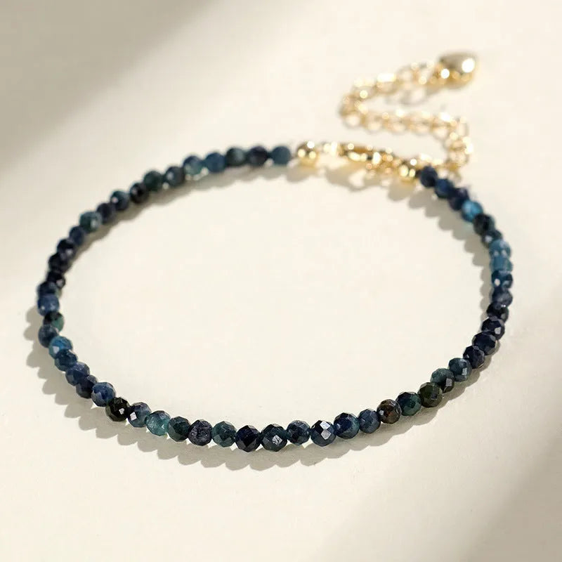 Close-up of a blue tourmaline beaded bracelet with 3mm stones and spacer beads on a wrist.