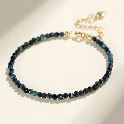 Close-up of a blue tourmaline beaded bracelet with 3mm stones and spacer beads on a wrist.