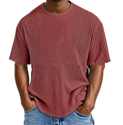 Man wearing a light blue waffle-textured cotton blend short sleeve t-shirt, casual pullover style.
