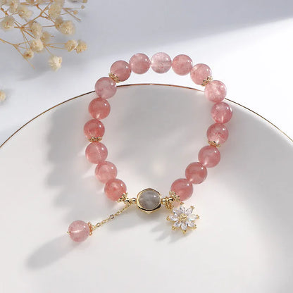 A Mori style crystal bracelet made with natural pink strawberry quartz stones and delicate electroplated floral charms.