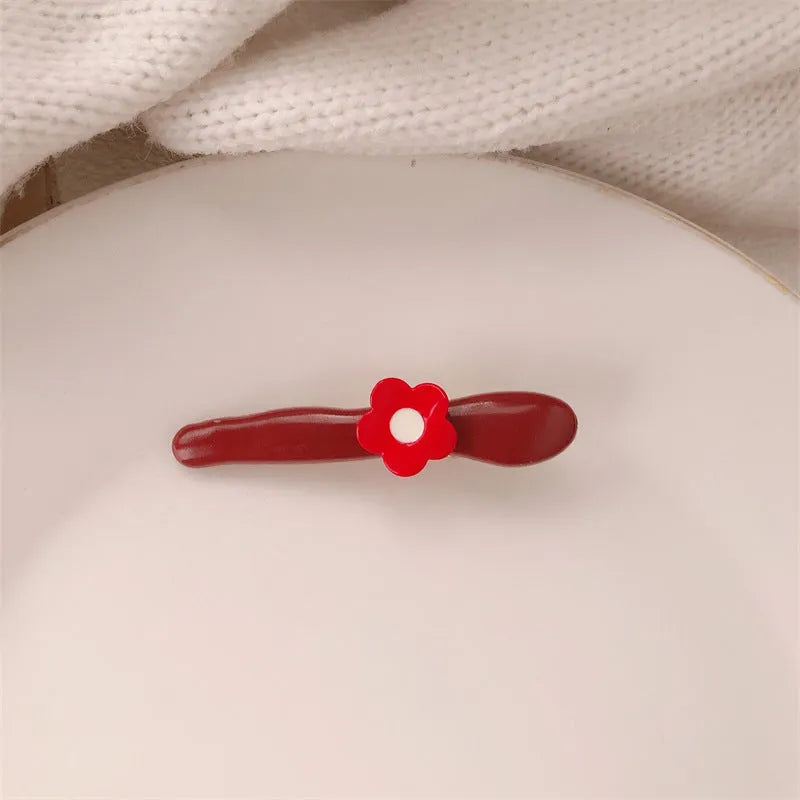 Red plastic hair clip with a 3D love heart and dots on a willow leaf-shaped base.