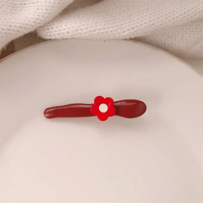 Red plastic hair clip with a 3D love heart and dots on a willow leaf-shaped base.