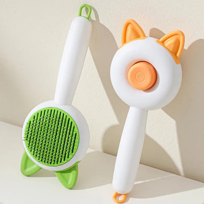 Greenish white pet grooming brush with stainless steel teeth, a push-button, and orange massage beads on the handle.