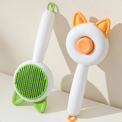 Greenish white pet grooming brush with stainless steel teeth, a push-button, and orange massage beads on the handle.