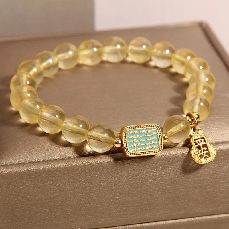 Women's bracelet made from yellow citrine crystal with rhinestone decoration on a white background.
