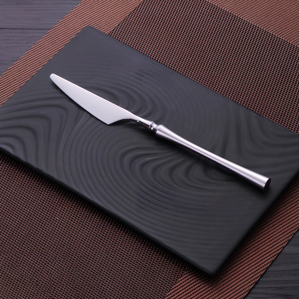 Four-piece stainless steel cutlery set showing main knife, fork, spoon, and teaspoon with mirror finish