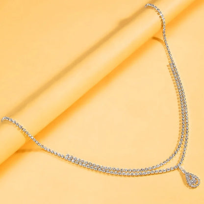 Gold water drop pendant waist chain with tassel detail and lobster buckle closure on white background