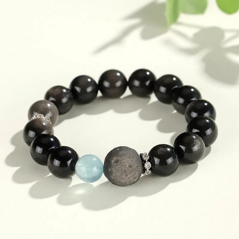 Silver stone crystal bracelet with diamond-shaped fox, cat head, and planet charms on white background.