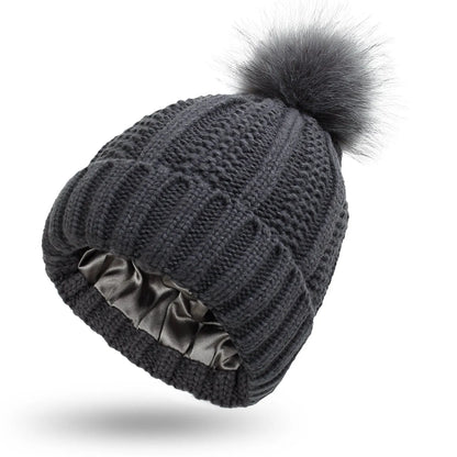 Wool knit beanie hat for women with faux fur pom pom and satin lining, shown in a wine red colour.