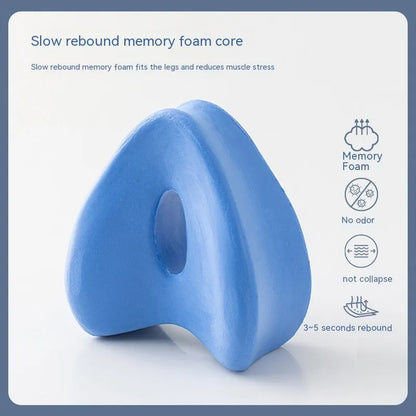 Dark blue jacquard heart-shaped memory foam leg pillow for adults on a bed.