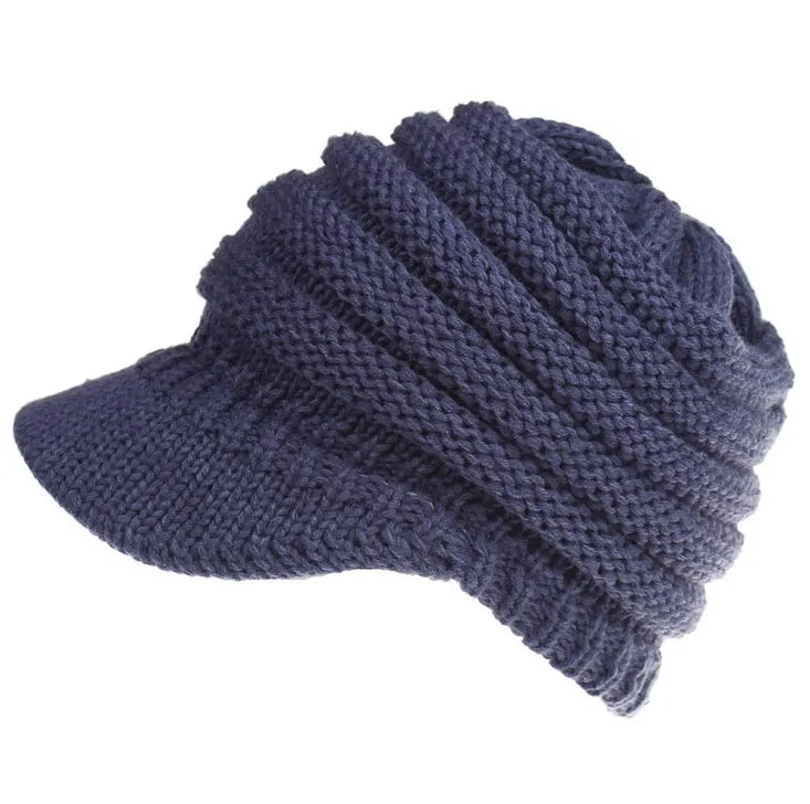 Woman wearing a light grey knitted ponytail beanie with her ponytail pulled through the hole in the back.