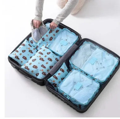Set of six coloured nylon packing cubes and flat pouches for travel organisation.