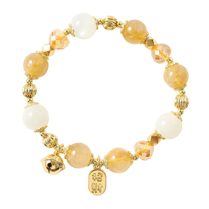 Gold-coloured rutilated quartz bracelet with a ringing bell charm on an adjustable band.