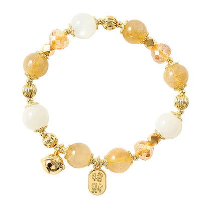 Gold-coloured rutilated quartz bracelet with a ringing bell charm on an adjustable band.