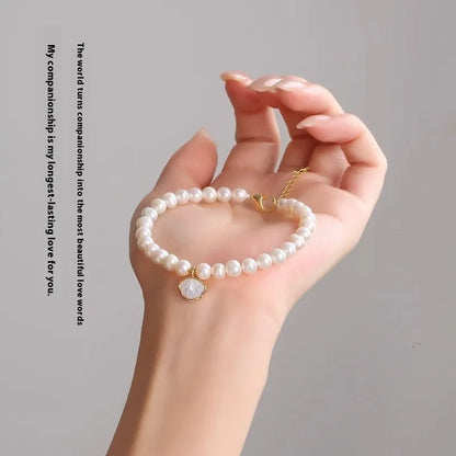 Women's freshwater pearl bracelet with fan-shell centrepiece on a 16cm elastic string or extension chain.