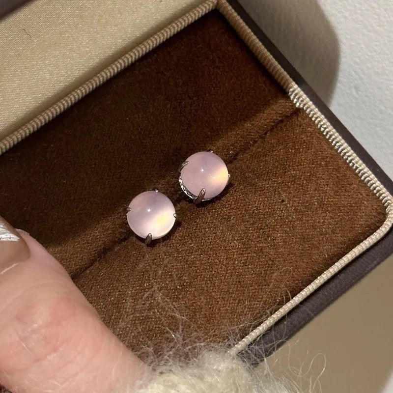 Close-up of a Chinese retro style stud earring with a round green chalcedony stone in a four-claw copper setting.