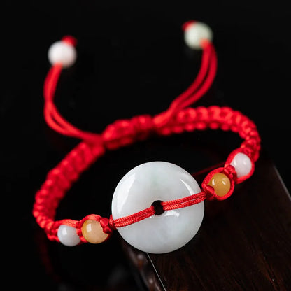 Round emerald green jade pendant on an adjustable red rope bracelet cord.