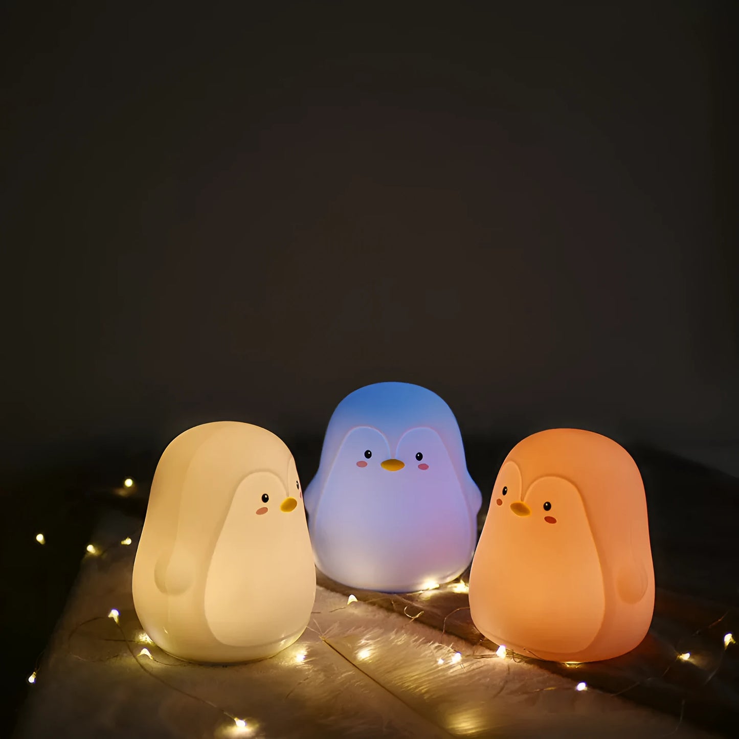 White silicone penguin-shaped USB rechargeable night light on a surface.