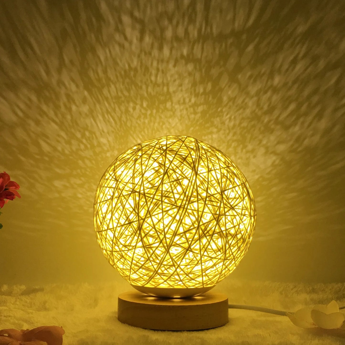 Spherical hand-knitted rattan table lamp with remote control on a wooden desk