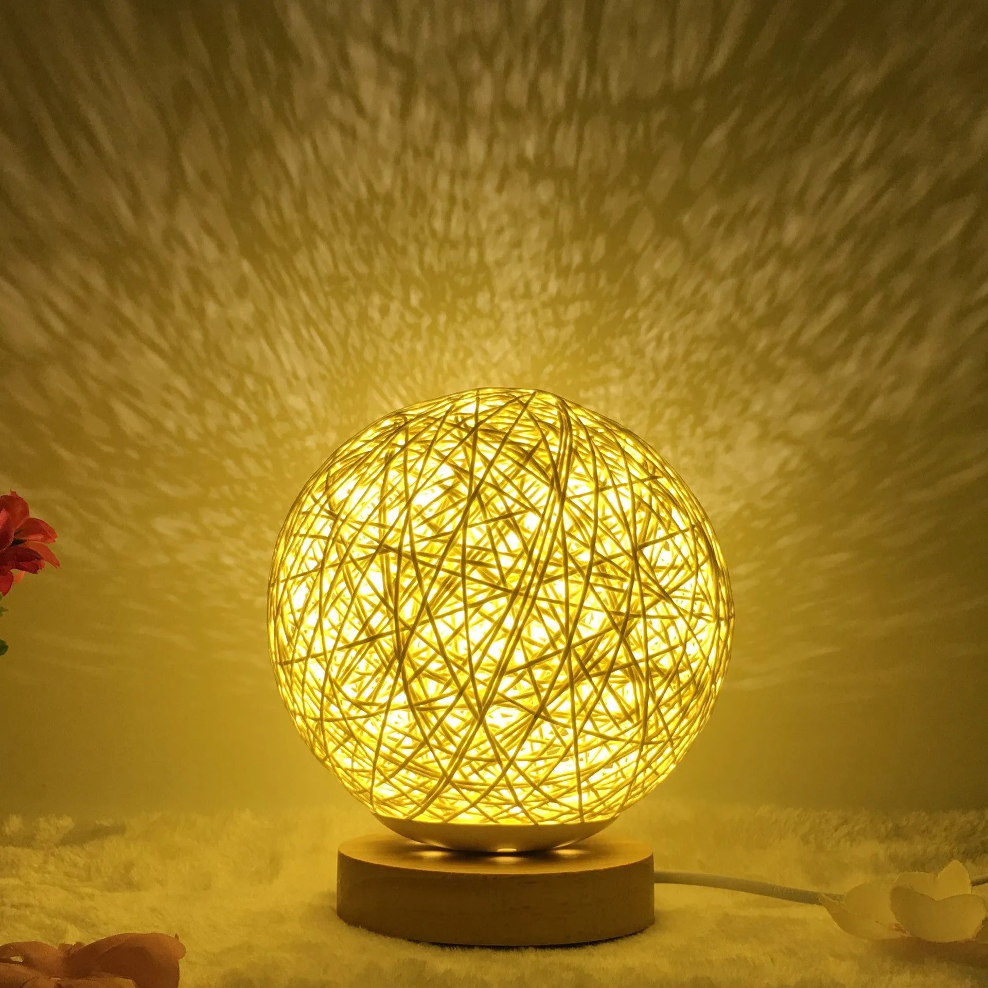 Spherical hand-knitted rattan table lamp with remote control on a wooden desk