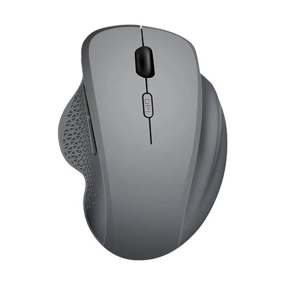 Compact grey wireless mouse with USB charging cable on a wooden desk next to a laptop.