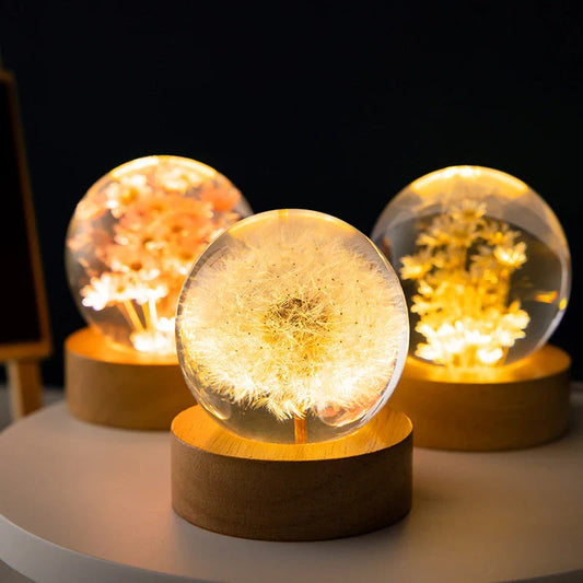 Enchanting 3D dandelion, yellow daisy, or red daisy flowers suspended in a clear crystal ball with a beech wood base, creating a mesmerizing desktop decor piece.