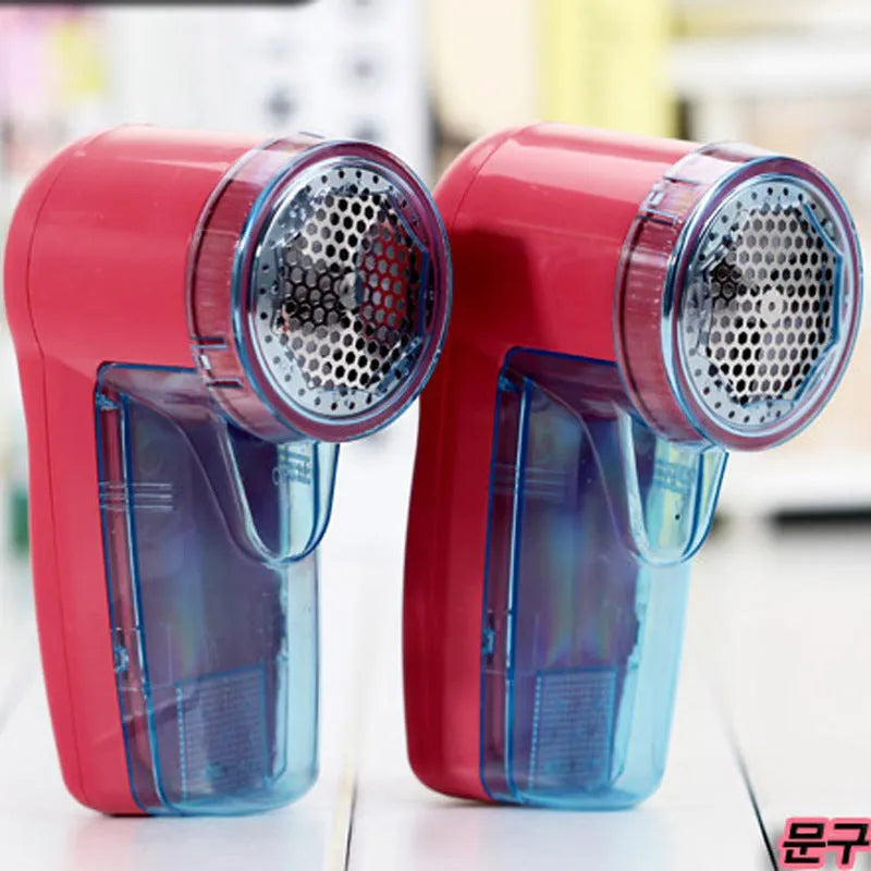 White portable electric lint remover on a blue sweater, showing compact size and shaver head.