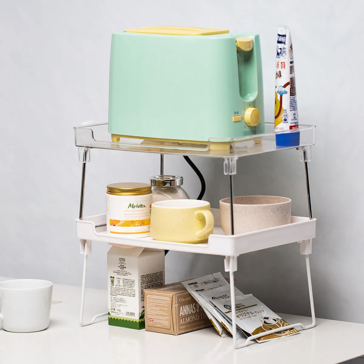 Transparent and white plastic kitchen supplies rack with multiple compartments for drawer and shelf organisation