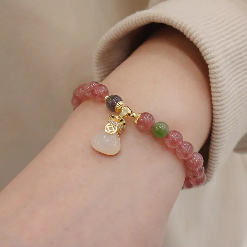 Women's strawberry quartz bracelet with geometric design and decorative purse charm on safety buckle closure
