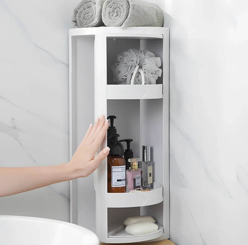 White triangle corner shelf with three tiers mounted in bathroom corner holding toiletries