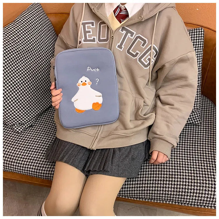 Blue tablet case with embroidered cartoon duck design showing zipper closure and cotton fabric texture