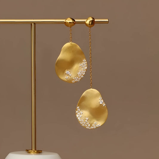 Asymmetric floral drop earrings with gold plating and zircon stone accents in silver colour