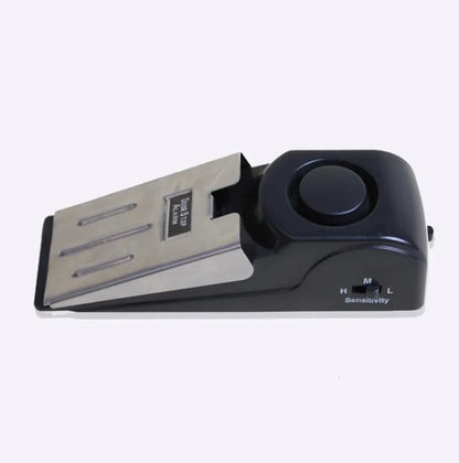 Portable wedge-shaped door stop alarm unit with stainless steel cover and sensitivity controls.