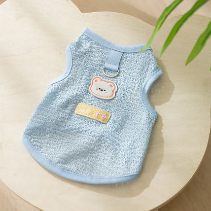 Green knitted cat clothing with a cartoon bear patch, showing hollowed-out breathable design.