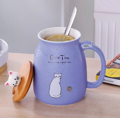 Pink ceramic mug with cartoon cat design, wooden lid, and stainless steel spoon on table