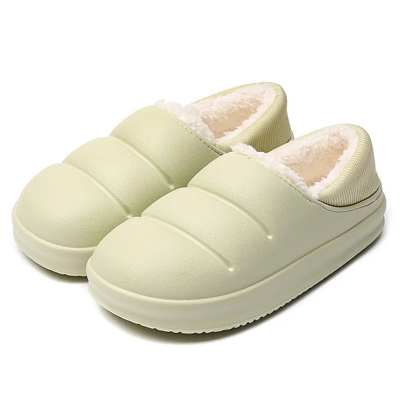 A pair of yellow EVA sleeve-style slippers with a plush lining and a textured non-slip sole, on a wooden floor.