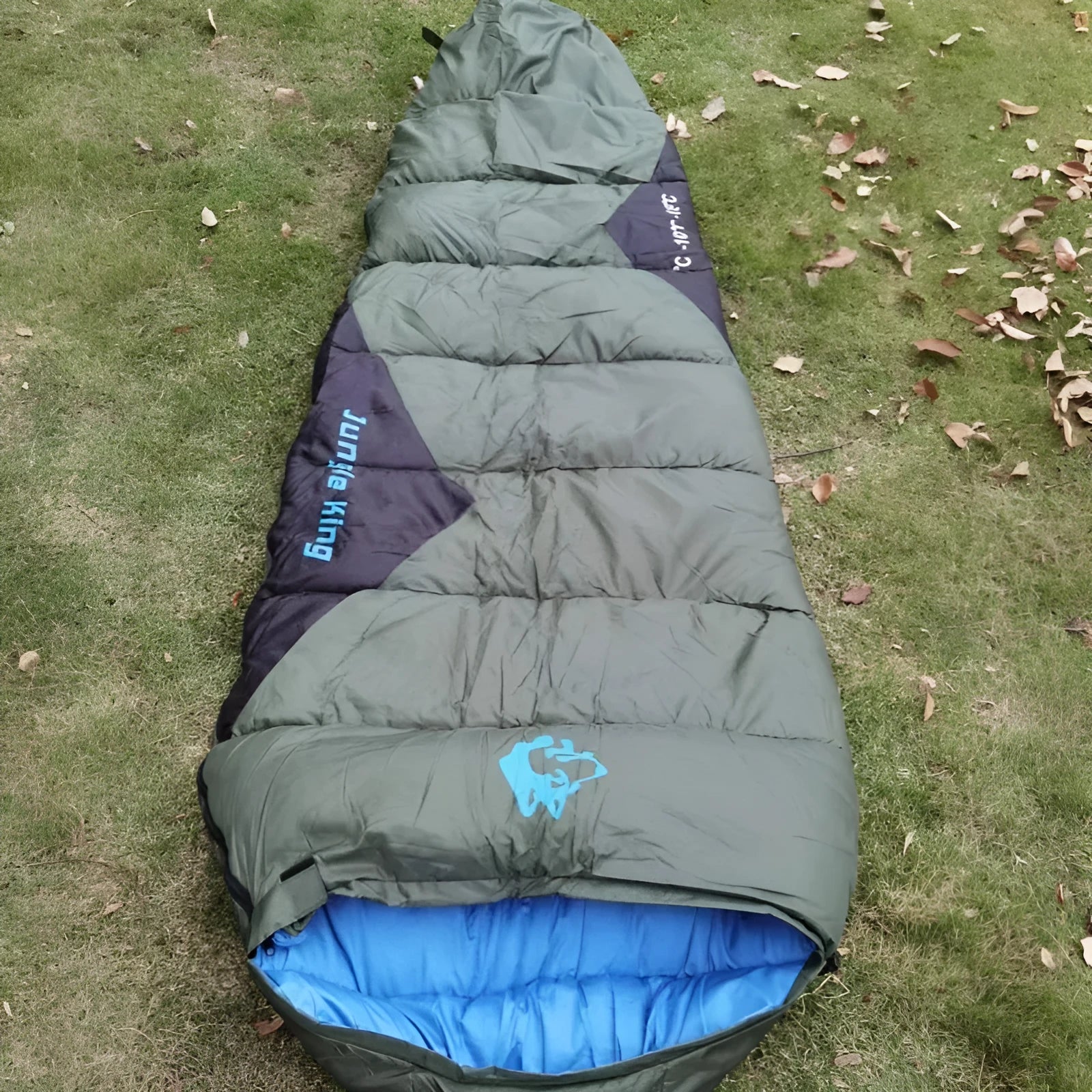 Outdoor mummy sleeping bag in army green with a compression sack, shown unrolled.