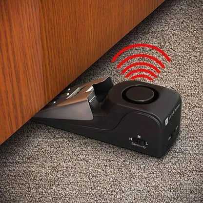 Portable wedge-shaped door stop alarm unit with stainless steel cover and sensitivity controls.