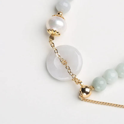 A geometric jade and pearl bracelet for women with a hand-finished peace buckle pendant.