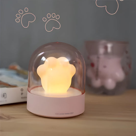 Grey cat paw shaped night light with USB port and button, glowing softly on a wooden desk.