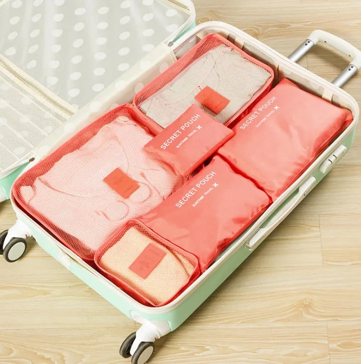 Set of six coloured nylon packing cubes and flat pouches for travel organisation.