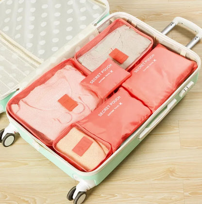 Set of six coloured nylon packing cubes and flat pouches for travel organisation.