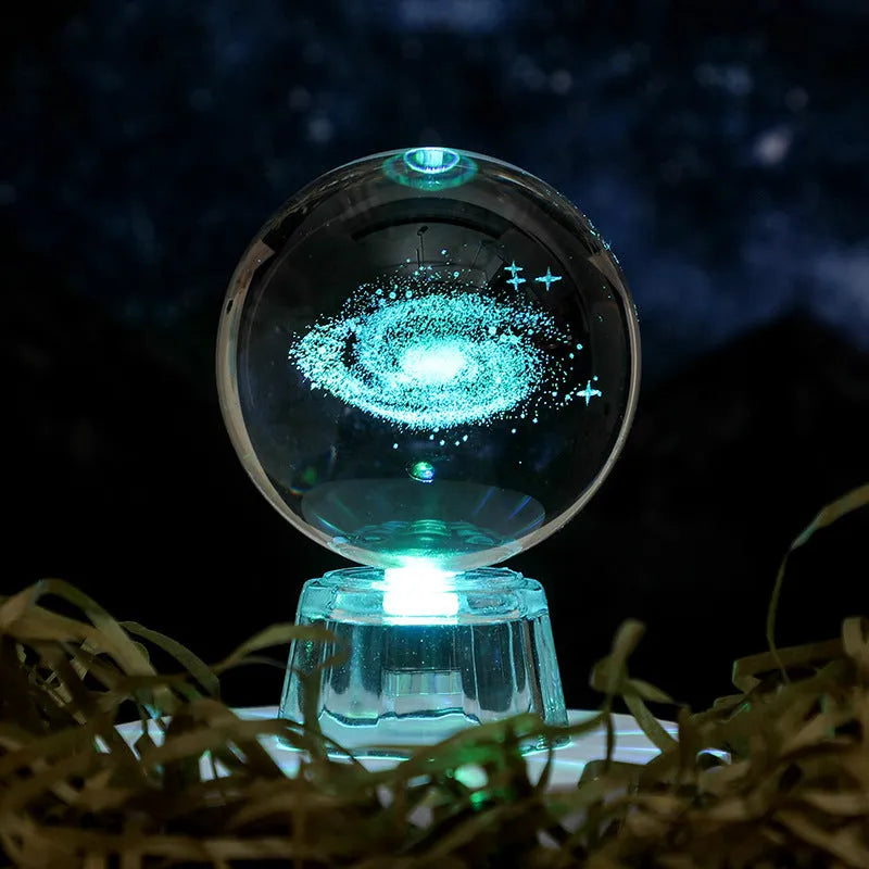 Transparent crystal ball ornament with inner carving of clouds, shown on a wooden table.