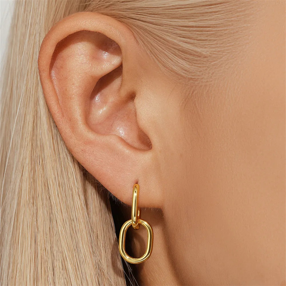 A pair of golden geometric clip-on earrings with a round design element on a white background.