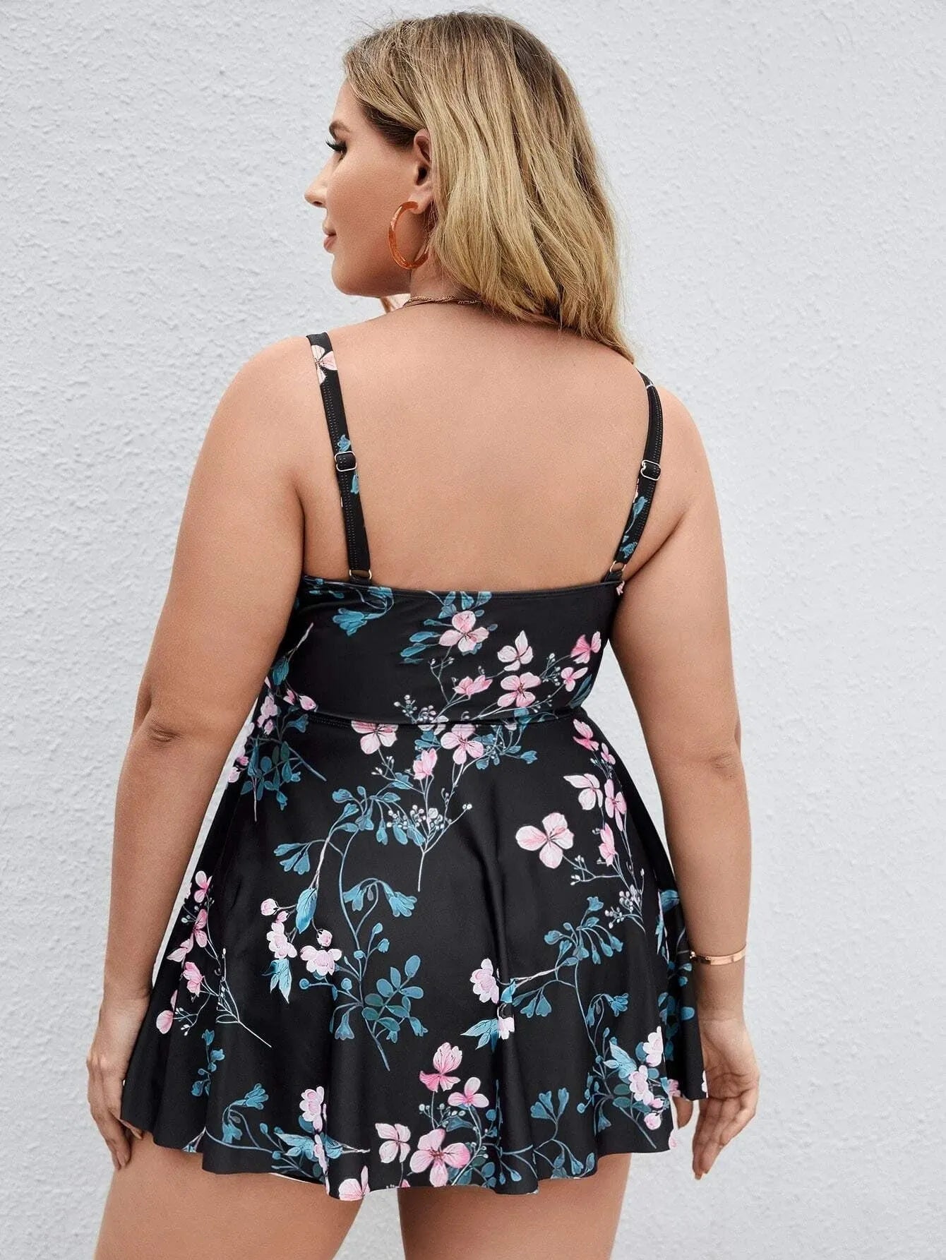 Women's one-piece swimsuit with a split colour floral print, shown on a mannequin.